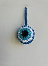 Load image into Gallery viewer, Crocheted eye-shaped object with blue and white colors on a light gray background
