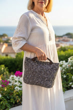 Load image into Gallery viewer, Person holding a textured handbag with a blurred outdoor background
