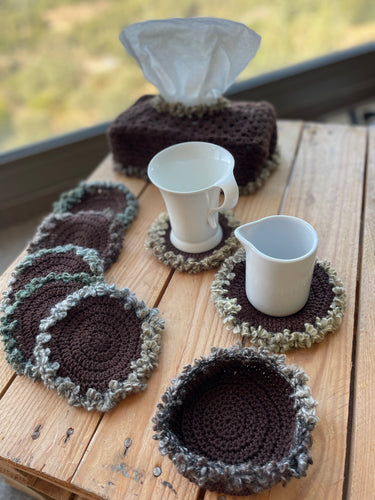 Set of crocheted coasters and a bowl on a wooden surface with a scenic background.