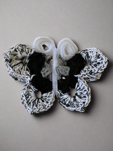Black and white crochet butterfly on a textured beige surface