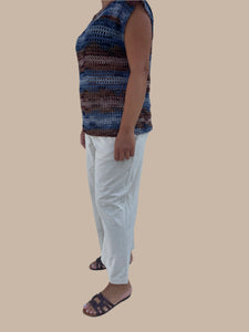 Person wearing a colorful dress and white pants on a tiled floor.