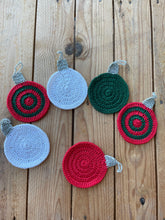 Load image into Gallery viewer, Set of crocheted coasters in red, green, and gray on a wooden surface
