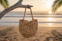 Load image into Gallery viewer, Brown crochet bag ona tree with the sea background 
