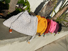 Load image into Gallery viewer, Colorful knitted headbands on a wooden stick against a concrete wall.
