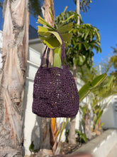 Load image into Gallery viewer, Purple crochet bag hanging on a tree branch with a blurred background

