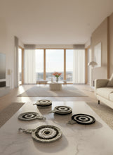 Load image into Gallery viewer, Set of black and white crocheted coasters on a wooden surface with a white mug.
