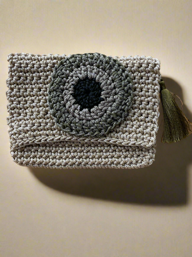 Crocheted clutch bag with a black center on a beige background