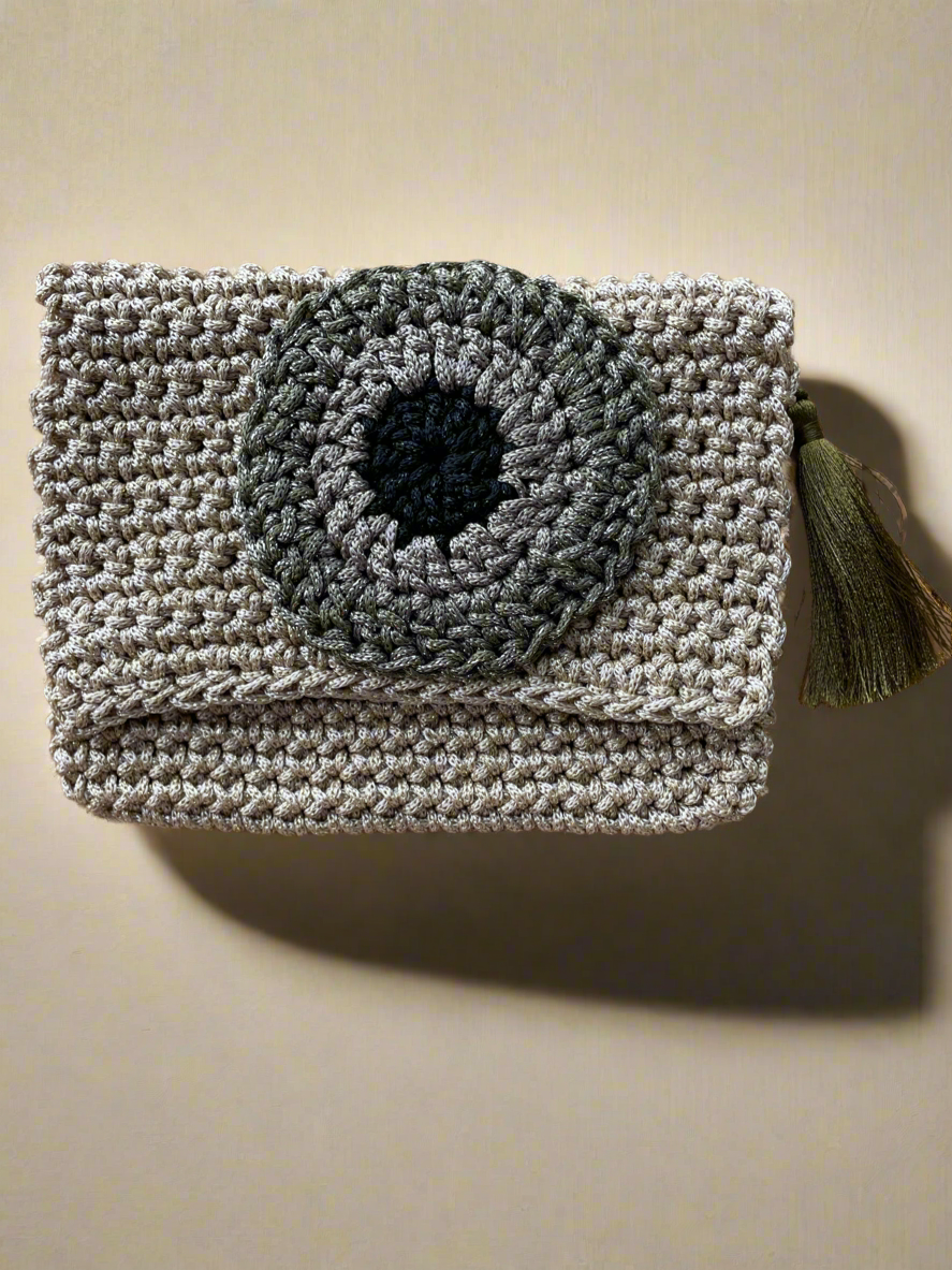 Crocheted clutch bag with a black center on a beige background