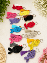 Load image into Gallery viewer, Colorful crocheted fish keychains on a light surface with flowers and leaves.
