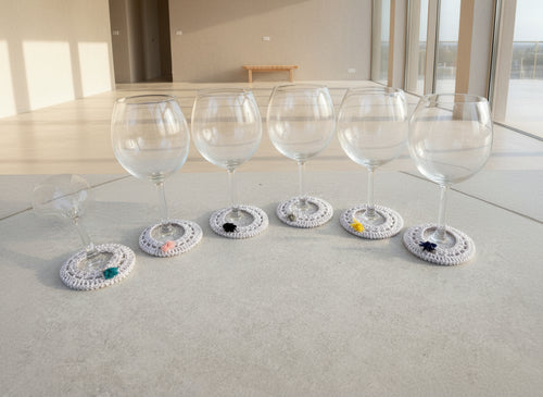 Decorative glass coasters with various embellishments on a gray surface