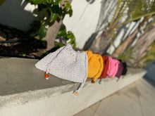 Load image into Gallery viewer, Set of colorful knit hats on a stone ledge with plants in the background
