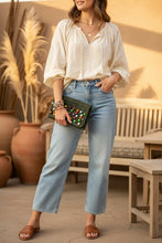 Load image into Gallery viewer, An olive green crocheted pouch or clutch decorated with colorful wooden beads, resting on a gray fabric surface.
