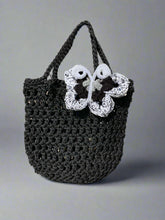 Load image into Gallery viewer, Black crochet bag with a white butterfly design on a textured surface
