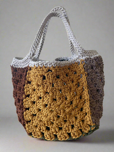 Crocheted bag with brown, gray, and mustard sections on a light background