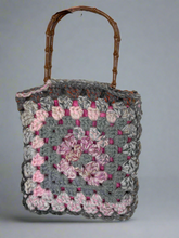 Load image into Gallery viewer, Crocheted bag with a floral pattern and wooden handle on a gray background
