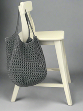 Load image into Gallery viewer, Gray crochet bag on a white chair against a gray background

