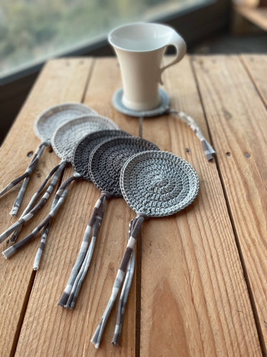 Set of crocheted coasters with tassels on a wooden surface