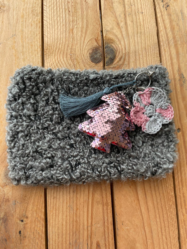 Gray textured pouch with decorative keychain on a wooden surface