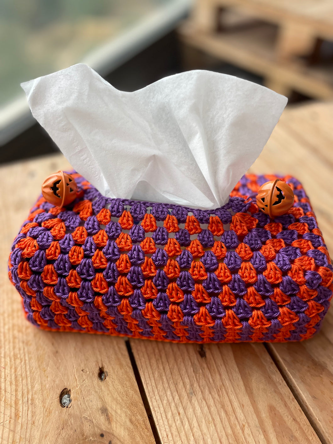Crocheted Halloween-themed tissue holder with white tissues on a wooden surface