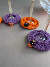 Load image into Gallery viewer, Halloween-themed crocheted coasters with small black cat decorations on a textured surface.
