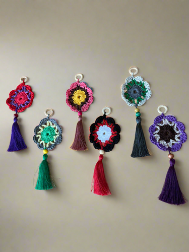 Colorful crocheted flower keychains with tassels on a beige background