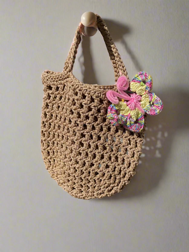 Brown crochet bag with a colorful butterfly attachment on a textured surface