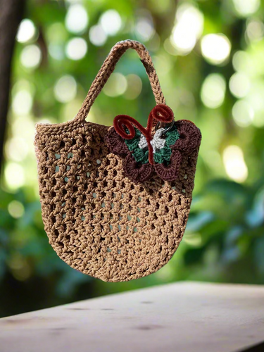 Brown crochet bag with a decorative butterfly on a stone surface