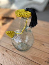 Load image into Gallery viewer, Glass bottle with a yellow and black decorative cap on a wooden surface
