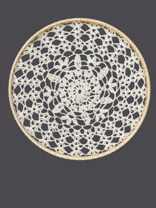 Round woven doily with black and white pattern on a gray background