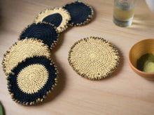 Load image into Gallery viewer, Set of crocheted coasters with blue and beige pattern on a wooden surface
