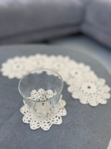Clear glass with decorative rings on a white doily on a gray surface