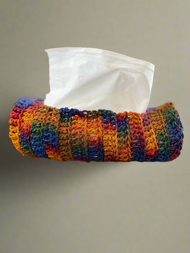 Colorful crocheted tissue holder with tissues on a gray surface