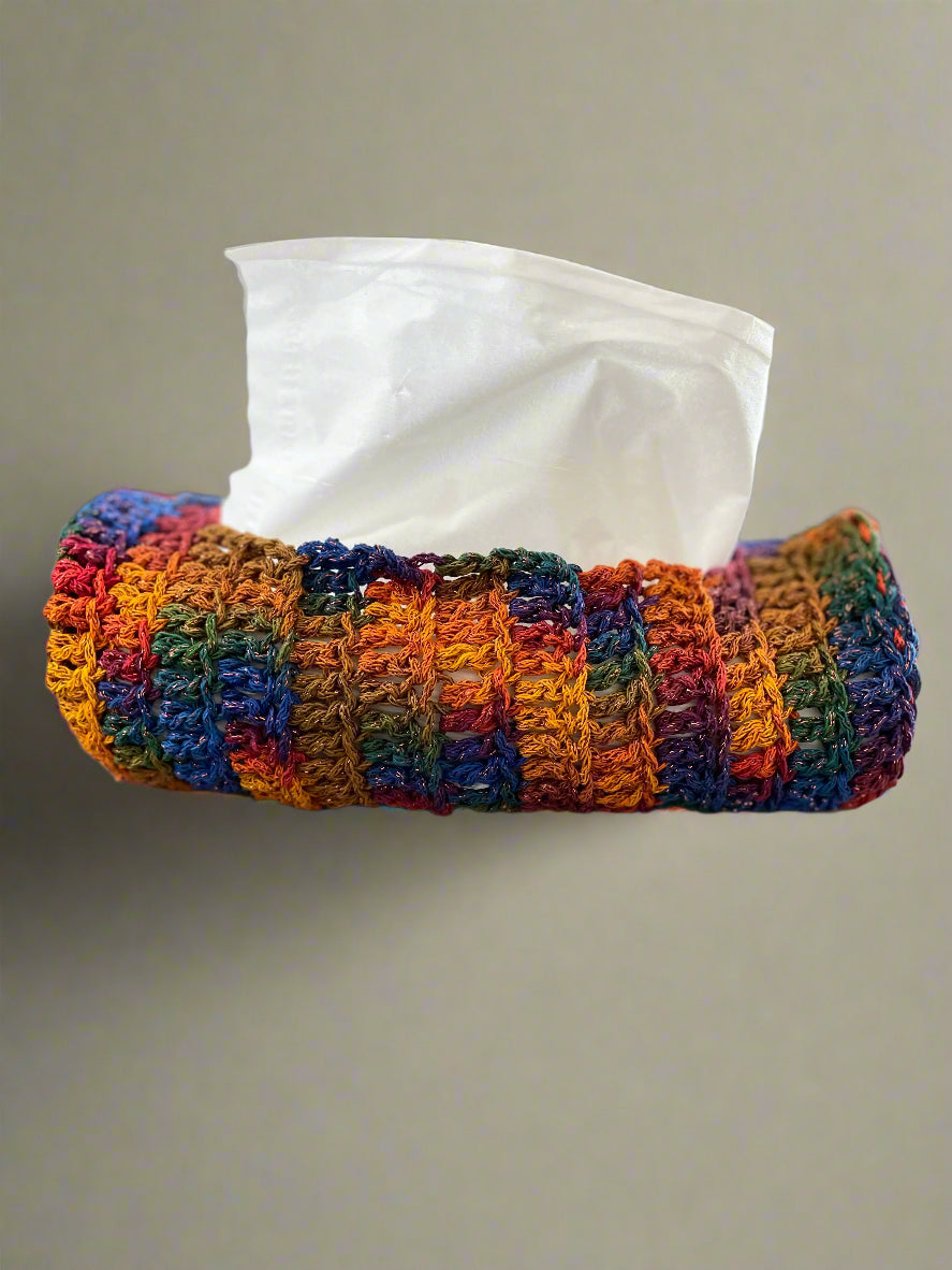 Colorful crocheted tissue holder with tissues on a gray surface