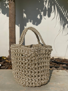 Woven handbag against a neutral wall with plant shadows