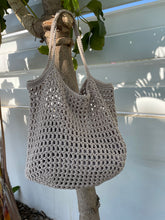 Load image into Gallery viewer, Crocheted bag hanging on a branch with a light background
