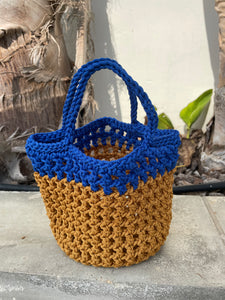 Two-toned blue and brown crocheted bag on a textured surface