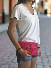 Load image into Gallery viewer, Person wearing a white t-shirt and denim shorts with a pink crochet clutch bag.
