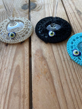 Load image into Gallery viewer, Three crocheted wine glass coasters in gold, black, and blue on a wooden surface.
