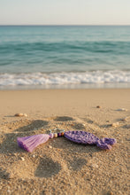 Load image into Gallery viewer, Purple crocheted keychain with tassel on a gray background
