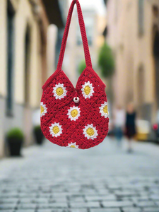 Red crocheted bag with floral patterns on a blurred street background