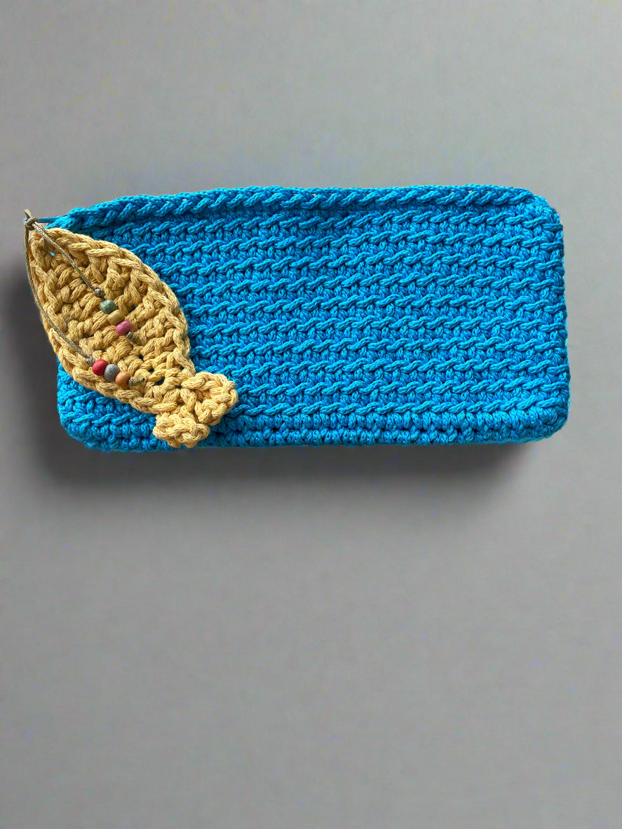 Blue knitted pouch with a yellow leaf design on a wooden surface