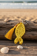 Load image into Gallery viewer, Yellow crocheted fish-shaped keychain with a tassel on a gray background
