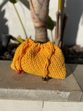 Load image into Gallery viewer, Yellow knitted pouch with red and brown buttons on a concrete surface

