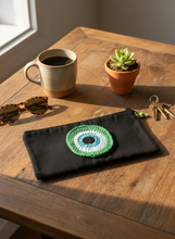 Load image into Gallery viewer, Black canvas pouch with green evil eye charm on table
