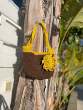 Load image into Gallery viewer, Crocheted brown and yellow bag hanging on a tree trunk with greenery in the background
