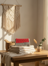 Load image into Gallery viewer, Handmade crochet clutch in earthy tones styled with natural bohemian elements
