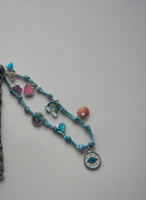 Load image into Gallery viewer, Bracelet with various charms on a gray background
