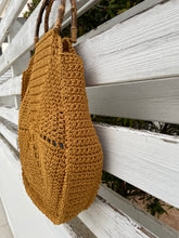 Load image into Gallery viewer, Brown woven bag on a sandy beach with ocean in the background
