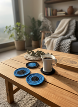 Load image into Gallery viewer, Lifestyle scene with blue and black crochet coasters
