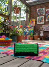 Load image into Gallery viewer, Multicolored crochet clutch in colorful creative setting
